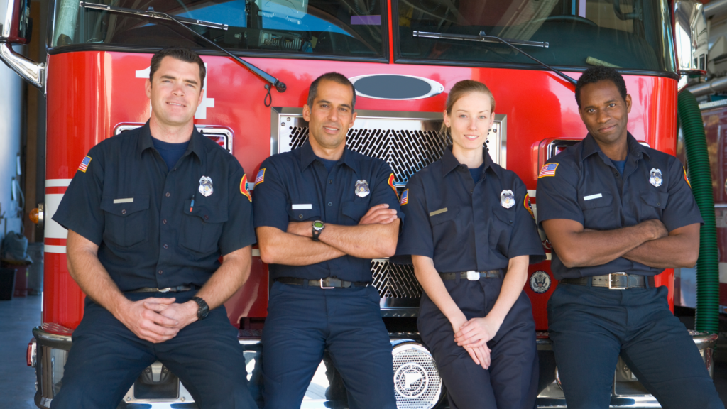 Front-line workers in front of firetruck. Front-line workers suffer from caregiver burnout at a rate that is higher than peers. 